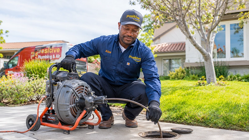 Positive Plumbing technician performing mechanical sewer cabling at a residential property in Orange County