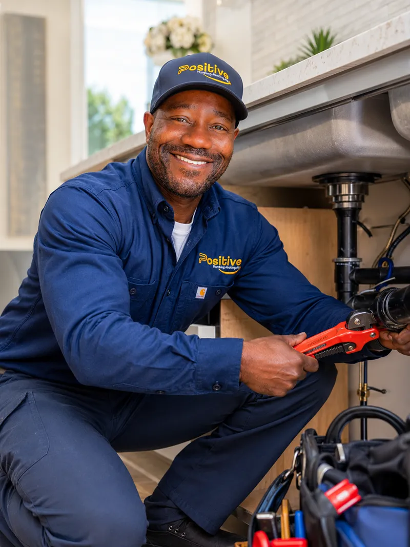 Positive Plumbing technician providing plumbing services under a kitchen sink in Irvine, CA