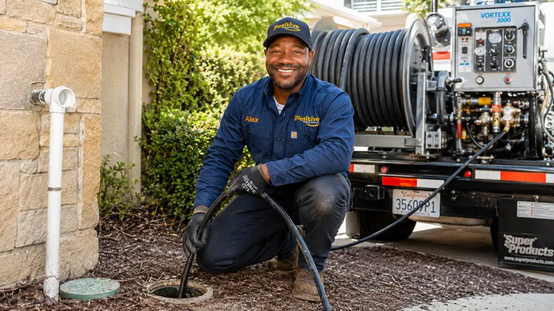 Positive Plumbing technician performing hydro jetting with professional sewer cleaning equipment